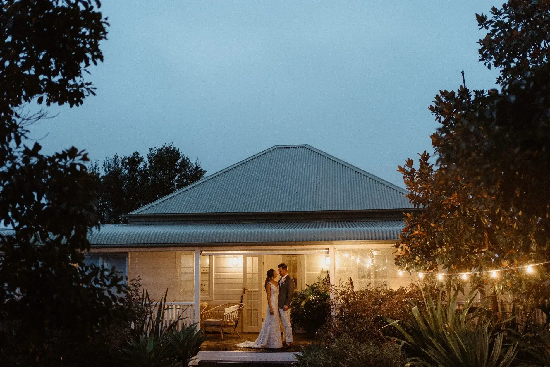 The marquee and farmhouse lit up at nightfall, Byron View Farm