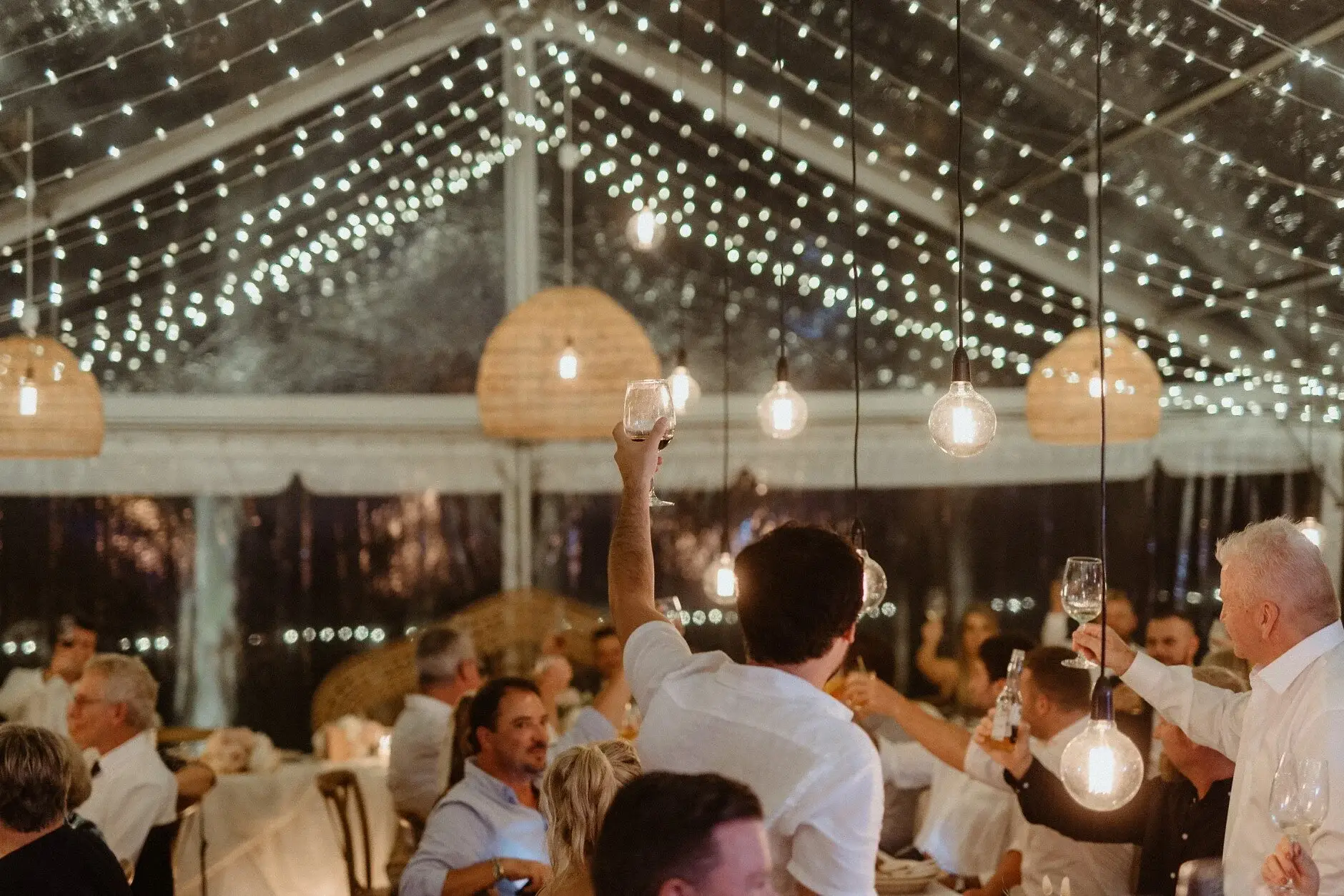 Guests at the tables under the festoon-lit marquee, Byron View Farm