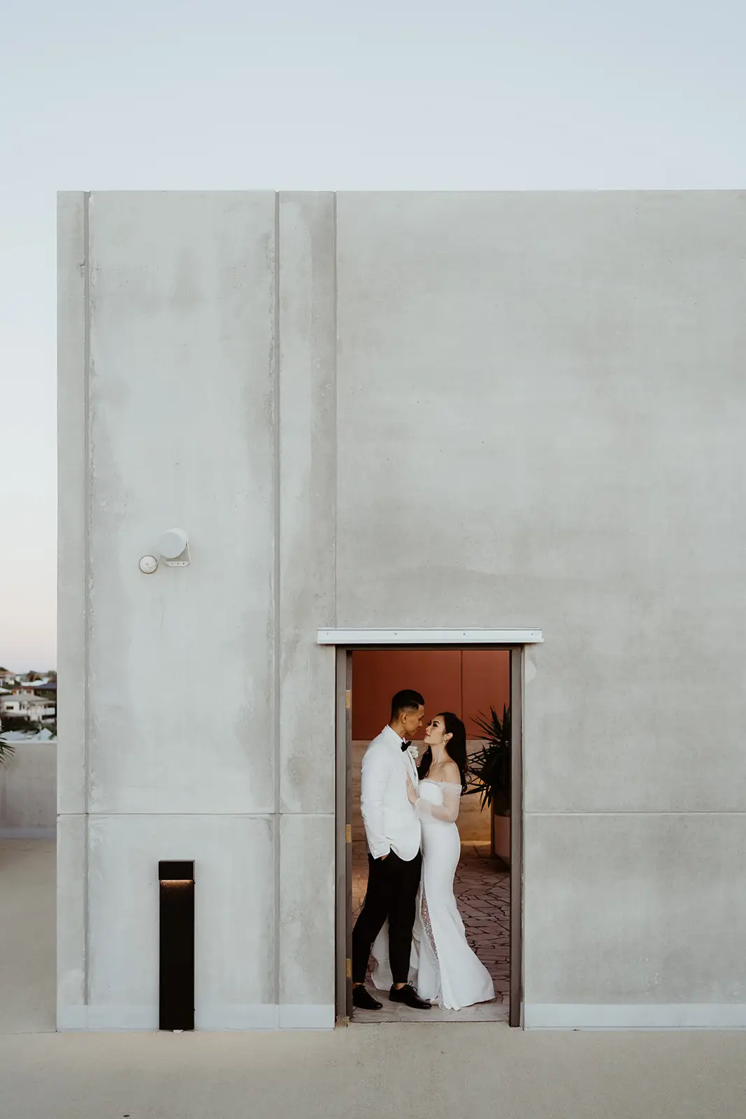 The couple together in a doorway set into the concrete wall, The Calile Hotel