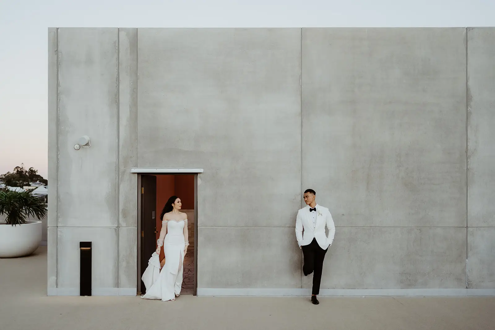 The couple apart on the tall pale concrete wall of the upper terrace, The Calile Hotel