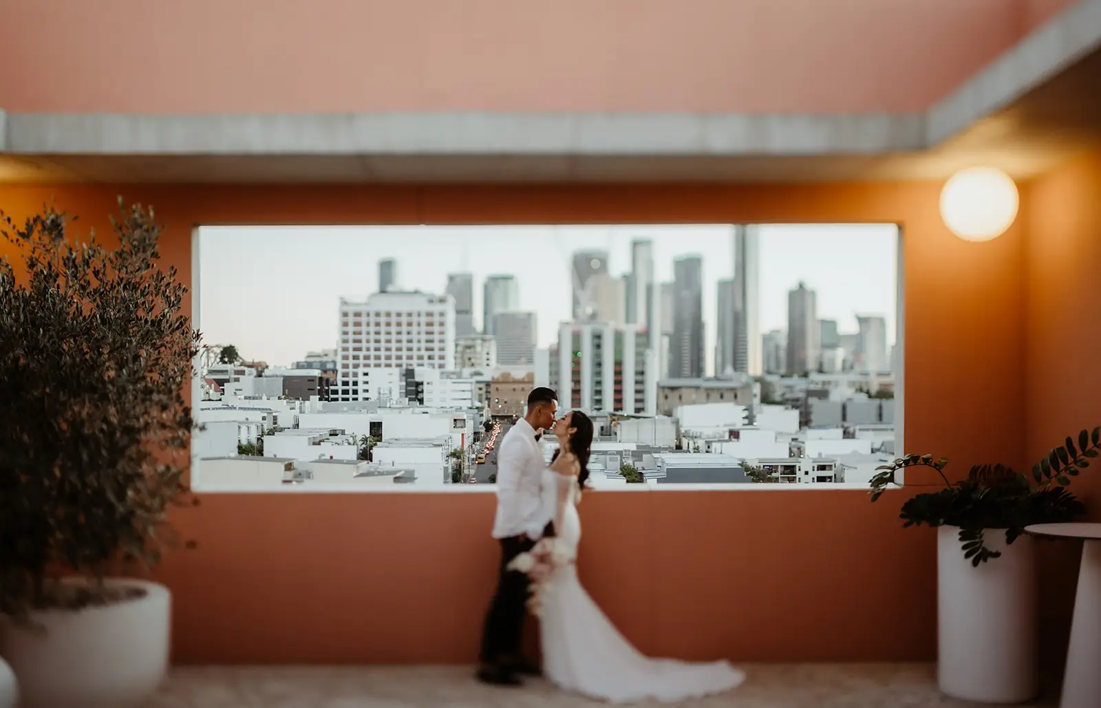 The city framed by the window of a terracotta-walled room, The Calile Hotel