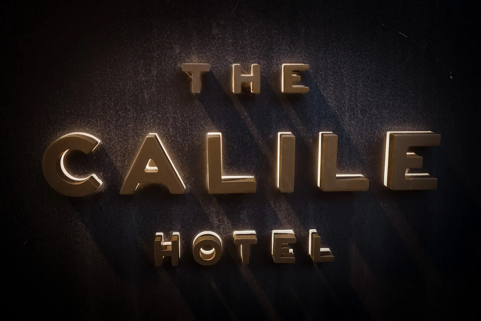 Brass lettering on the dark lobby wall, The Calile Hotel