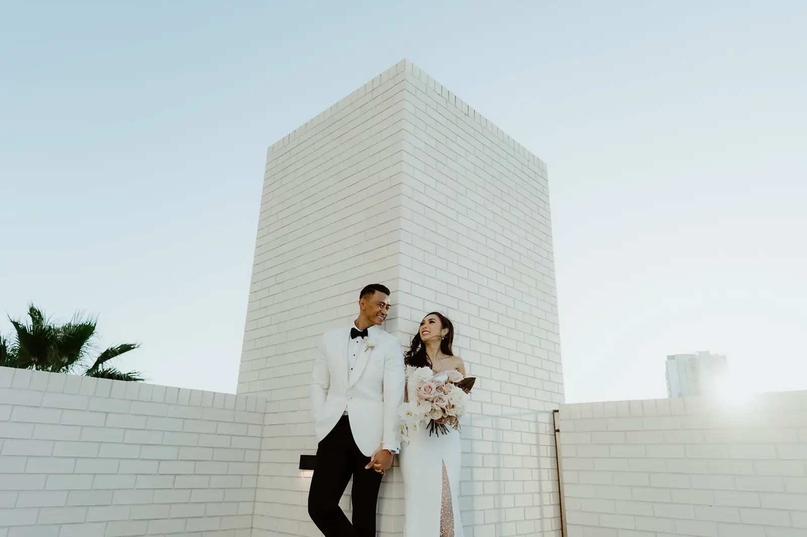 The couple against the white brick in full sun, The Calile Hotel