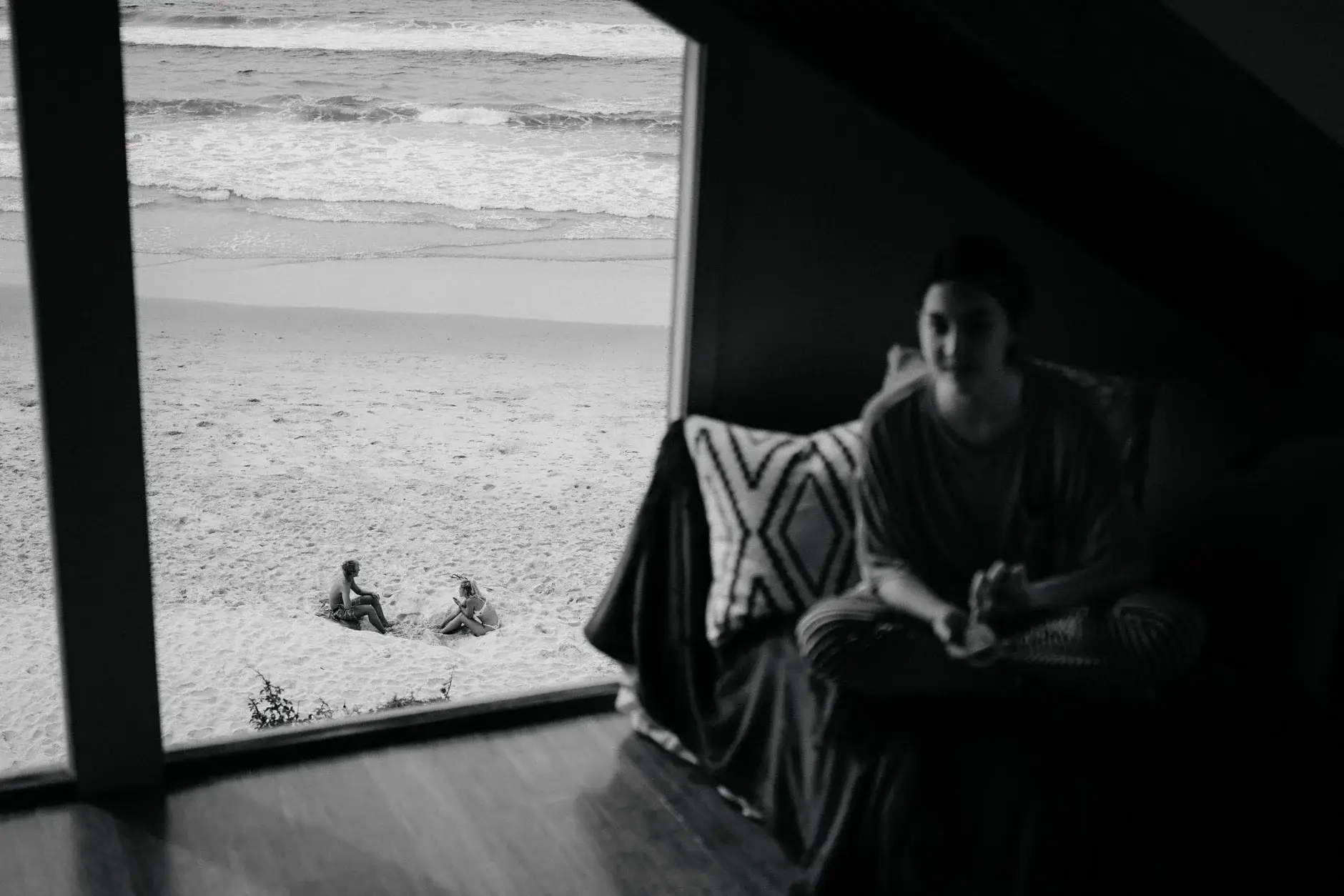 Jack sitting in the doorway looking out to the beach, black and white