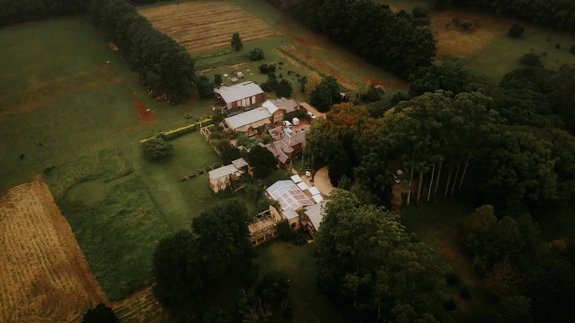Aerial view of the Deux Belettes farmhouse and cottages set among green hills, Byron Bay hinterland