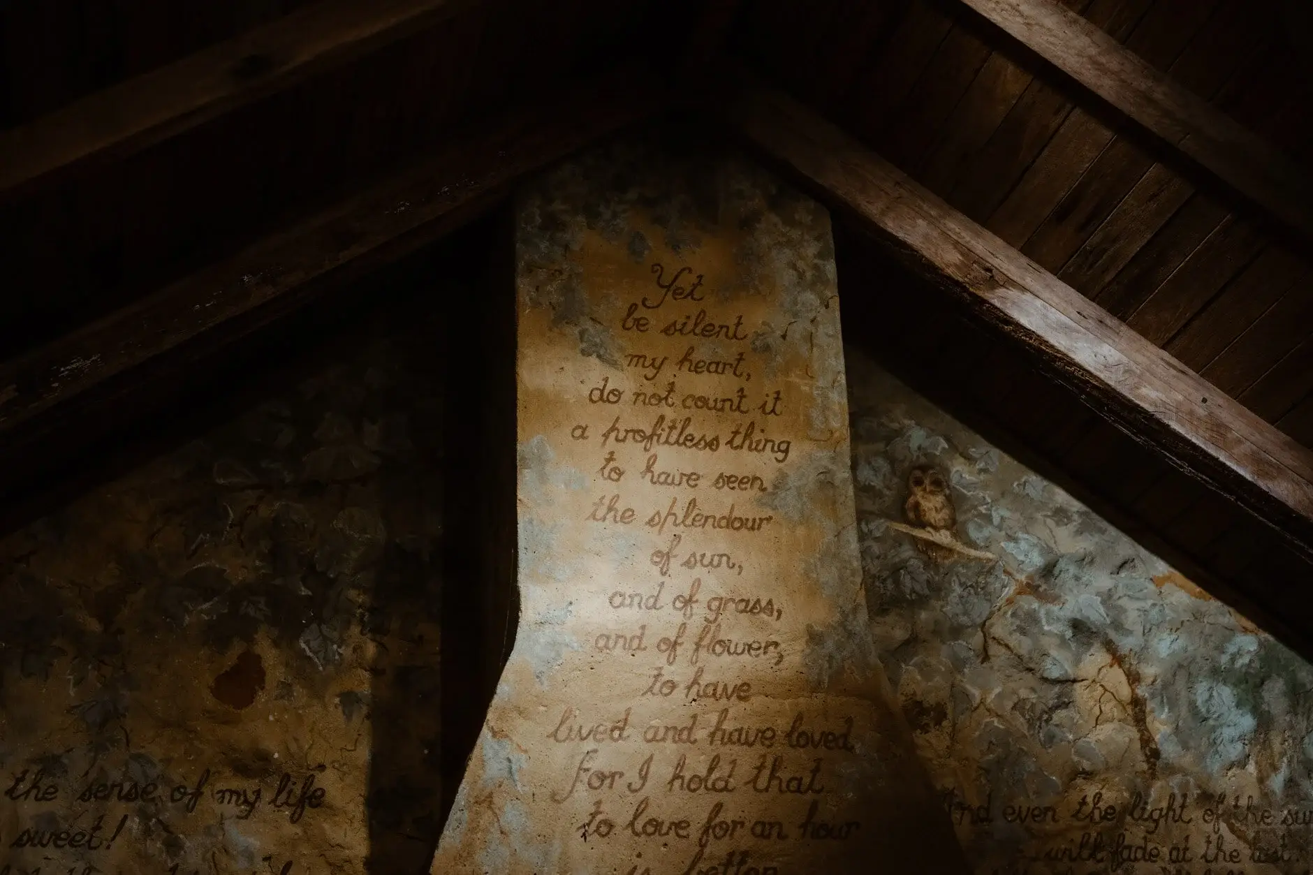 Verse hand-painted onto the stone chimney breast beneath the timber rafters, Deux Belettes