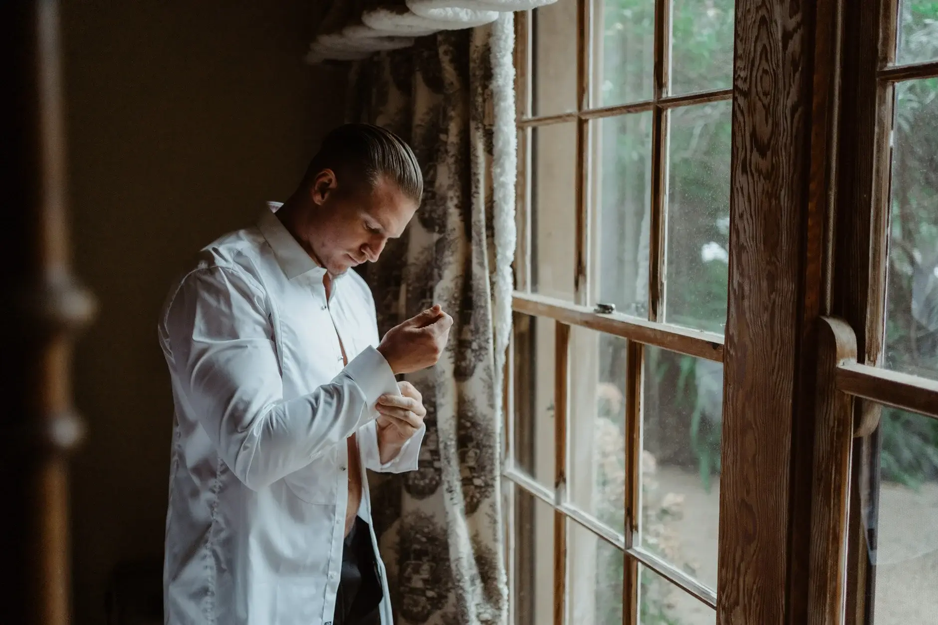 John fastening his cuffs by the window of the French House, Deux Belettes