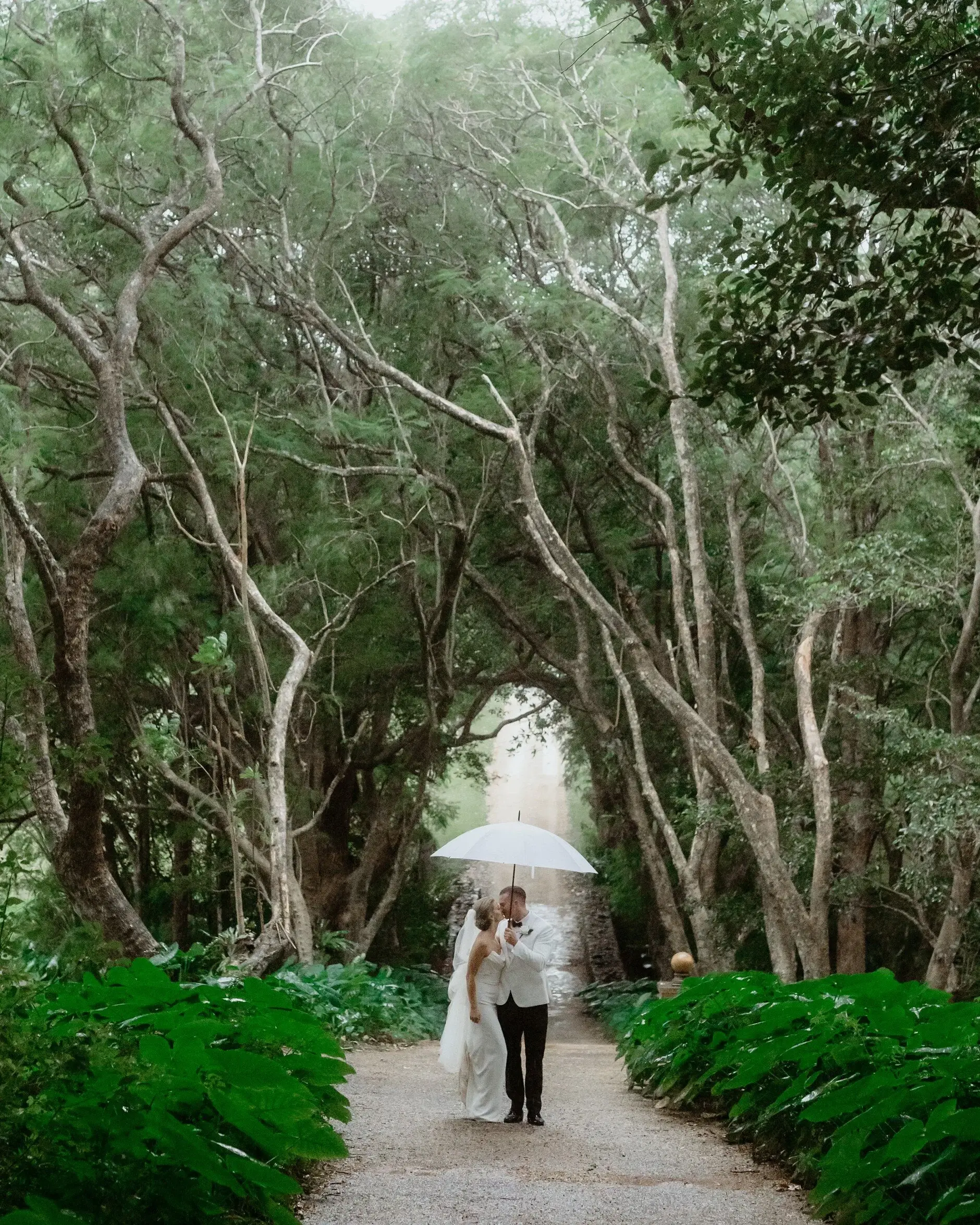 Maddie and John walking a leafy garden path under an umbrella, Deux Belettes