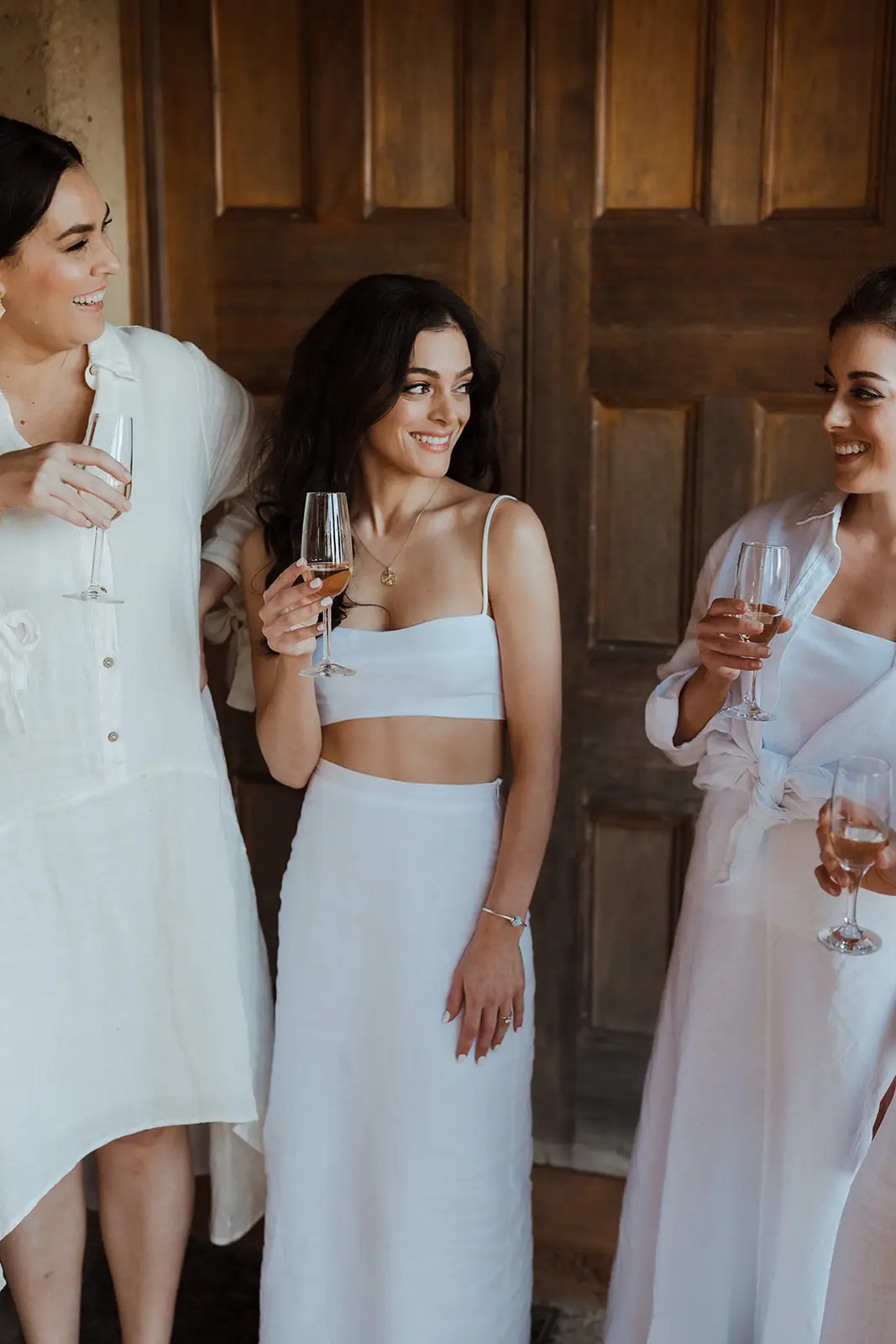 The wedding party in white with champagne in the doorway of the hall, EarthHouse