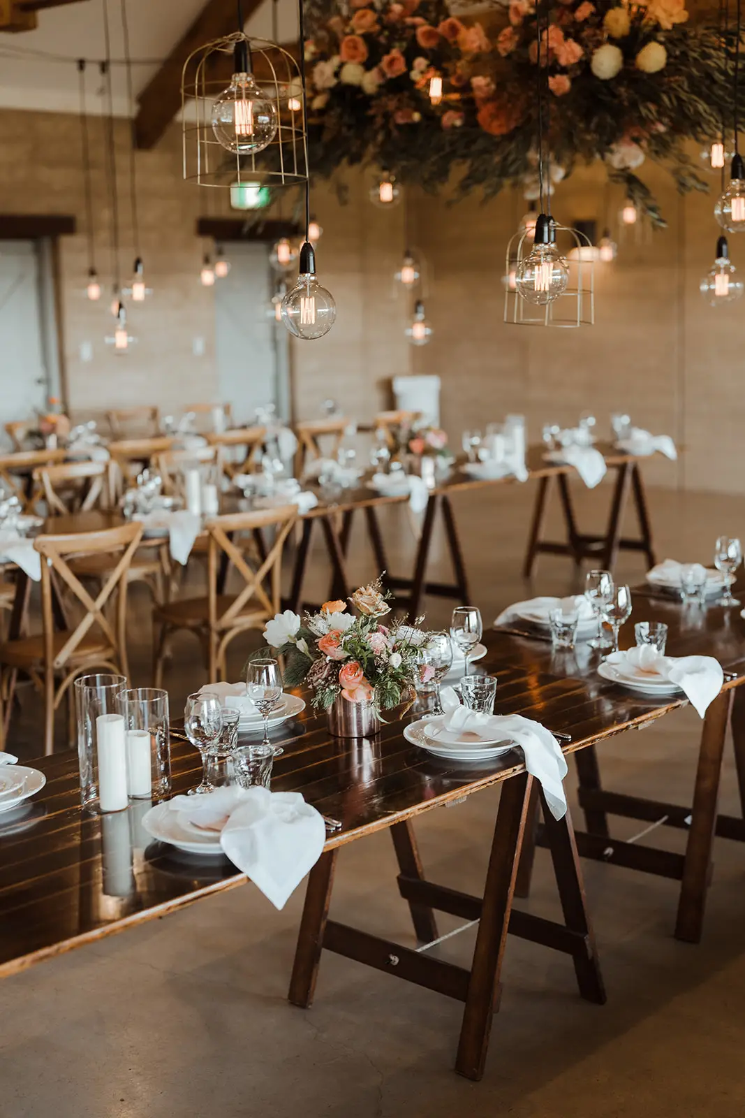 The rammed-earth hall set for dinner with cross-back chairs, festoons and hanging florals, EarthHouse, Clunes