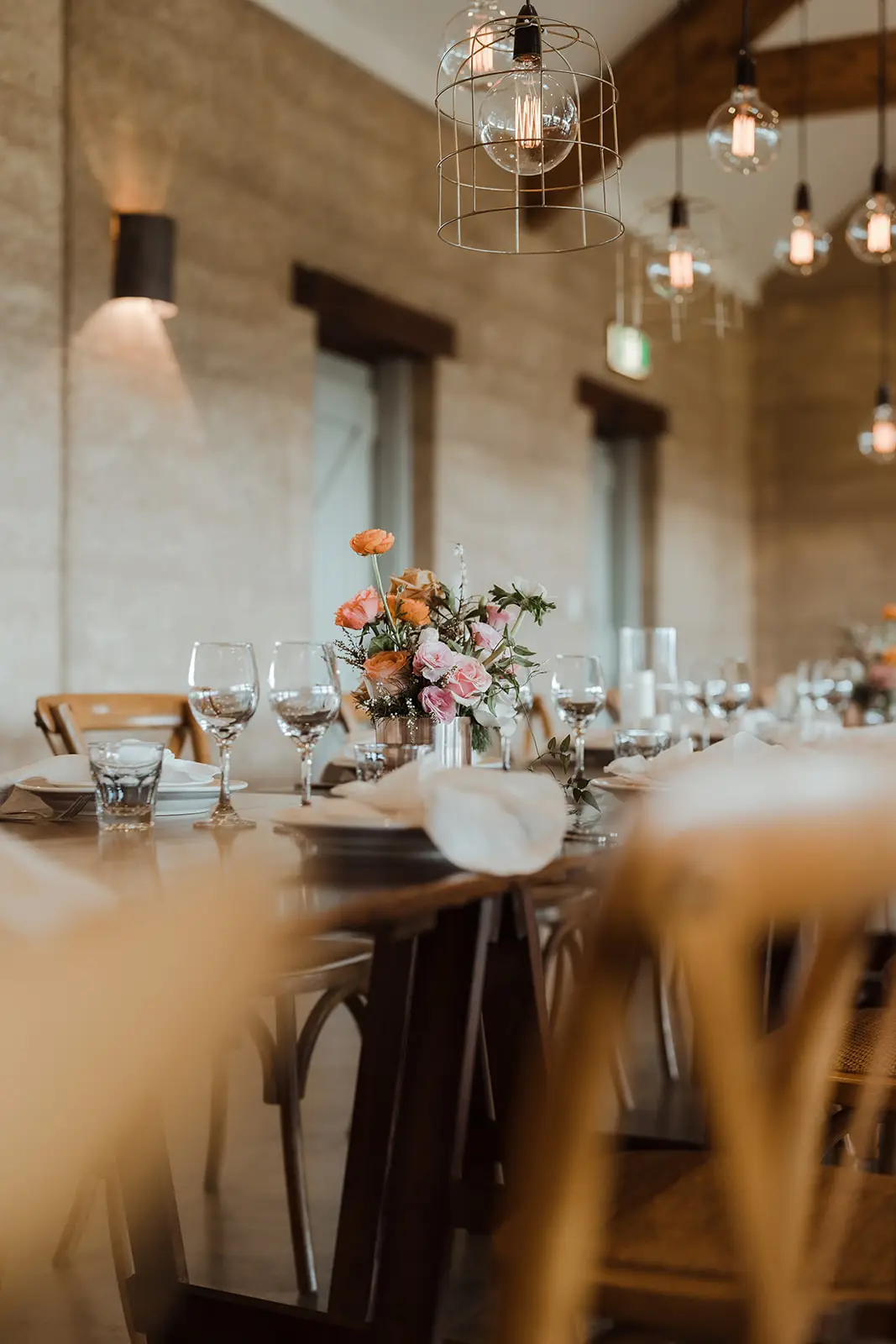 One of the tables set with bud vases under the pendant lights, EarthHouse