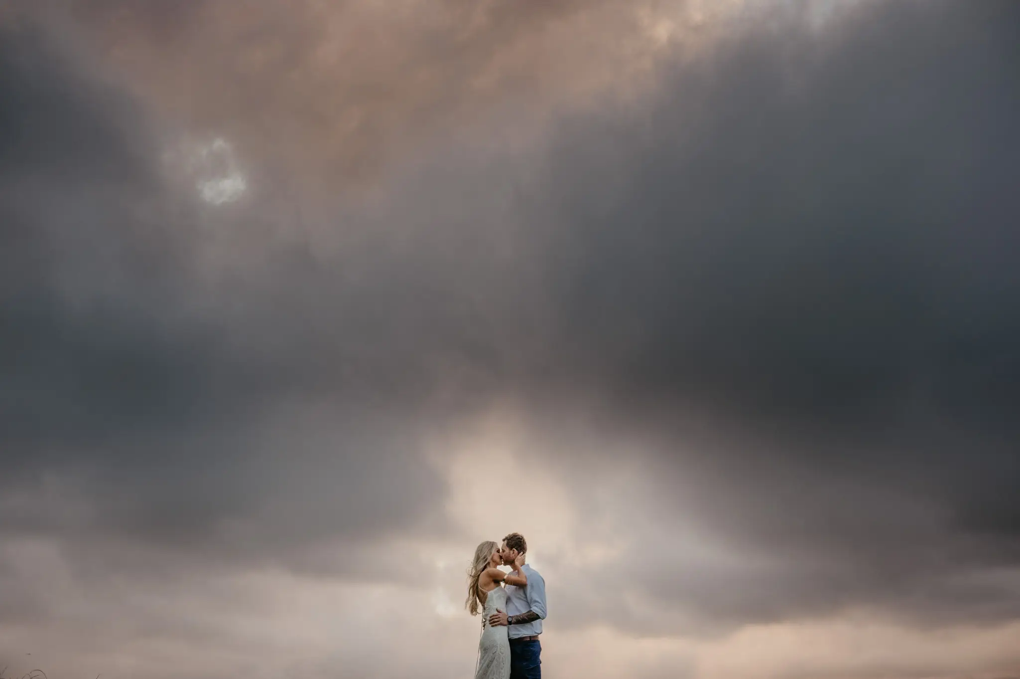 Couple embracing under a towering storm cell