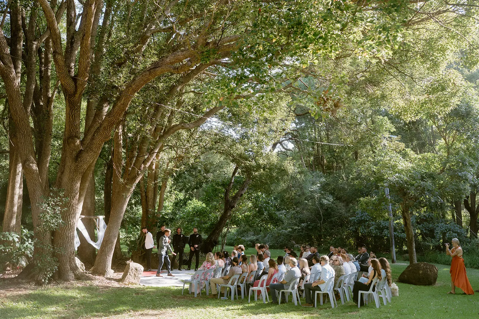 The ceremony from the side, chairs set out on the grass beneath the canopy, Ewingsdale Hall