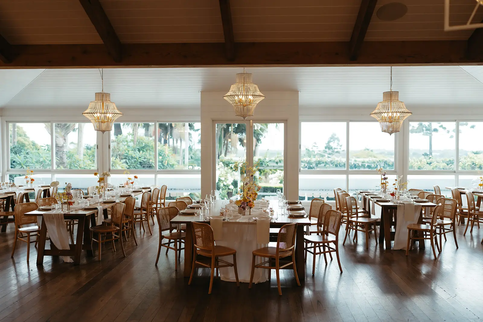 Round tables set under the timber beams and woven pendant lights, windows to the garden, Fig Tree Restaurant