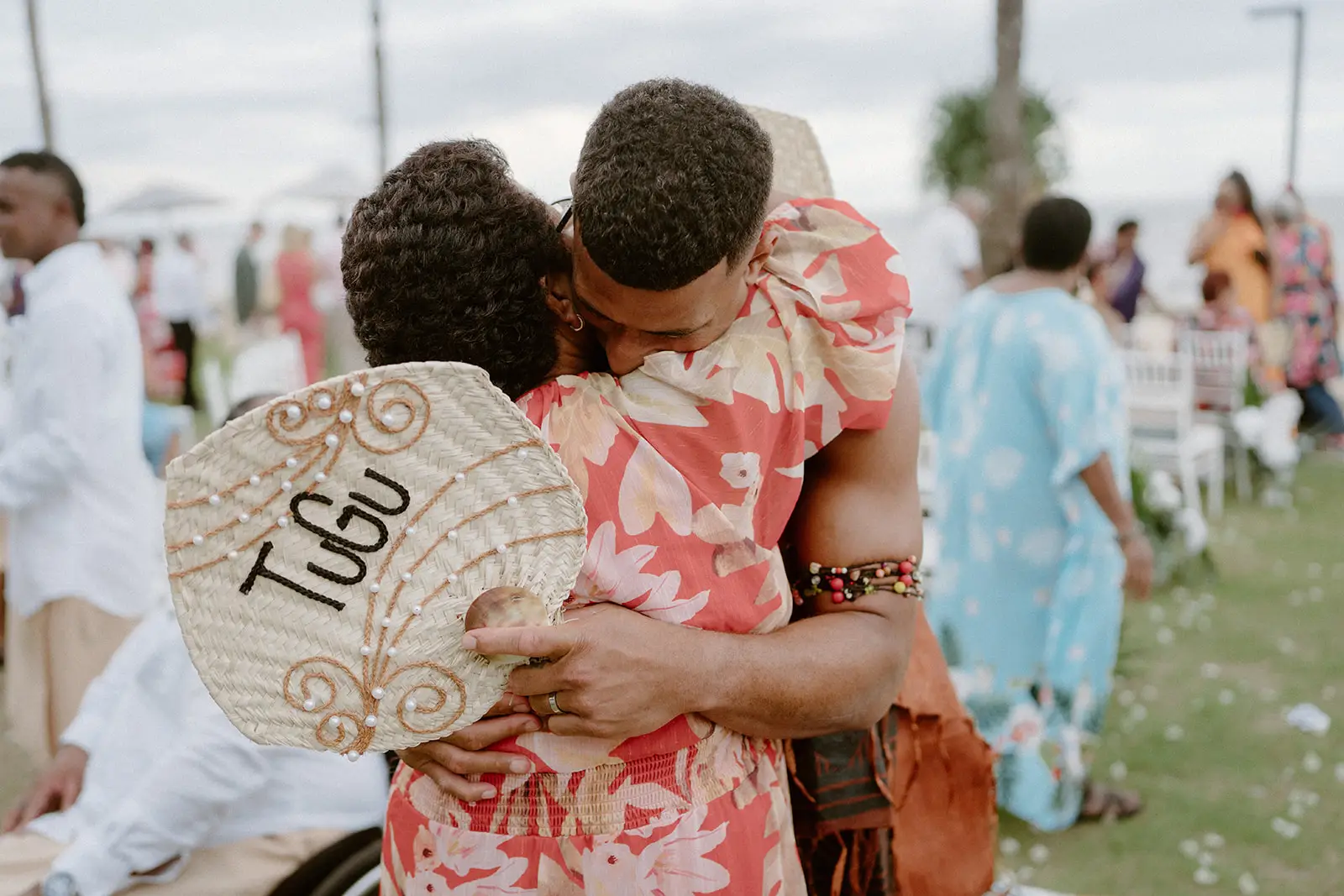 A guest with a woven fan embracing the couple, Nadi Bay
