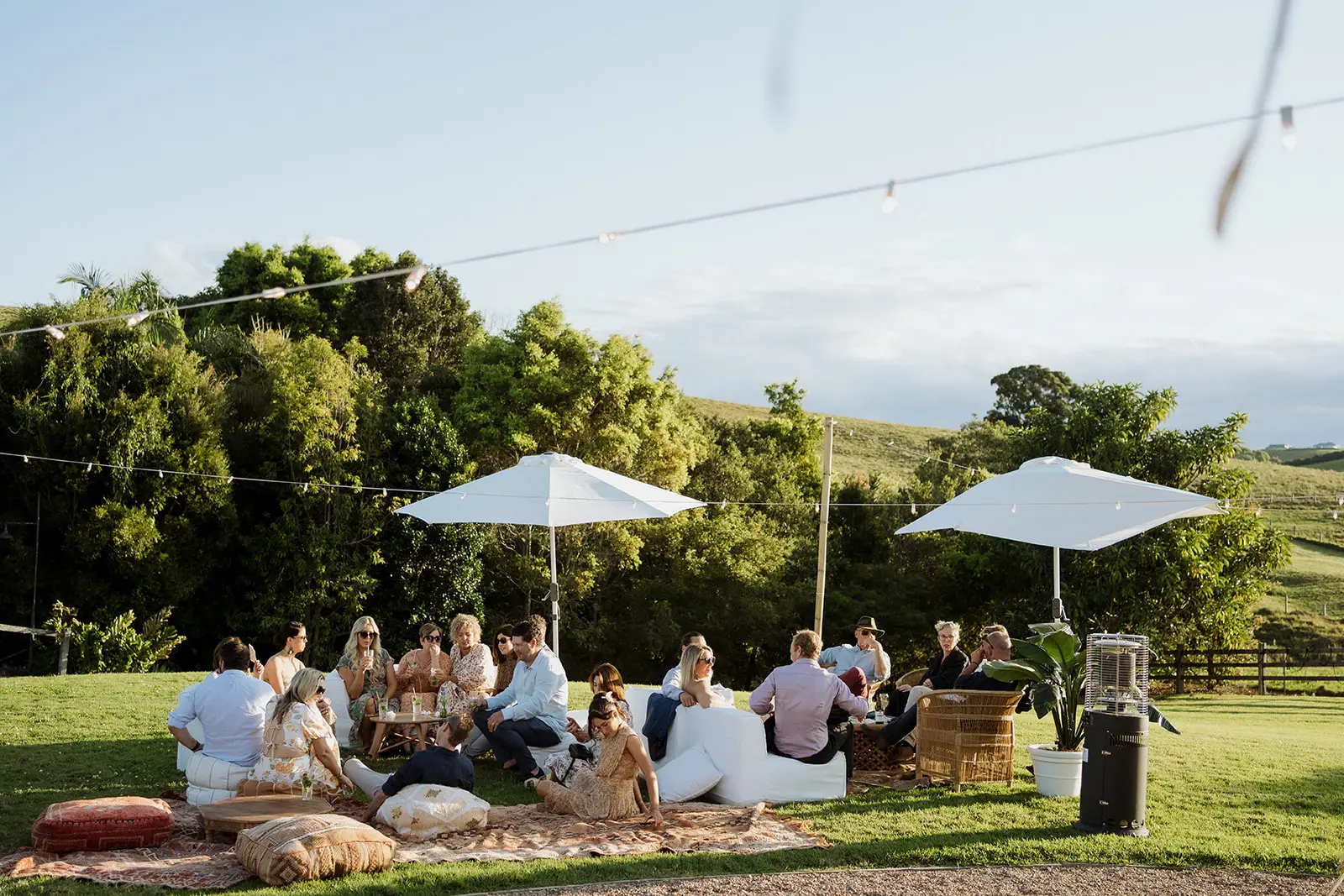 Guests on the lawn under white umbrellas with the hinterland beyond, Forget Me Not