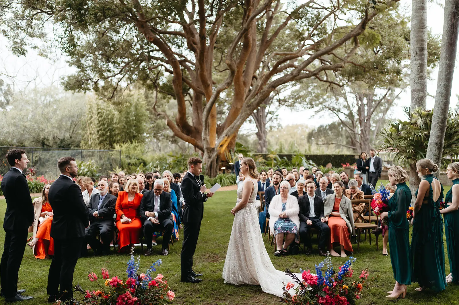 A garden ceremony on the lawn beneath the old figs, guests in bright colours, Gabbinbar Homestead, Toowoomba