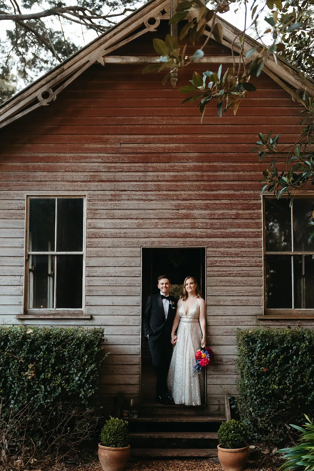 The couple in the doorway of the weathered timber cottage, Gabbinbar Homestead