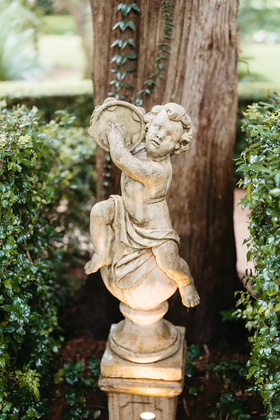 A weathered cherub statue against a tree in the garden, Gabbinbar Homestead