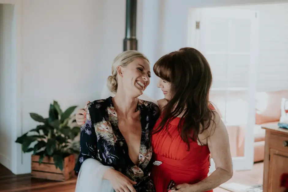 Jessica laughing with a bridesmaid in the getting-ready house, Goremans Road