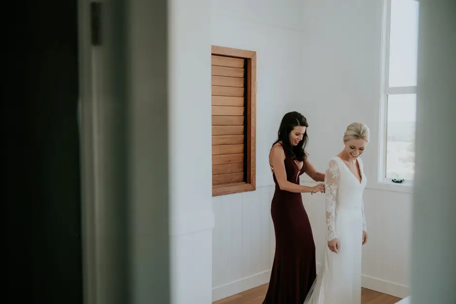 A bridesmaid doing up the back of Jessica's gown, Goremans Road
