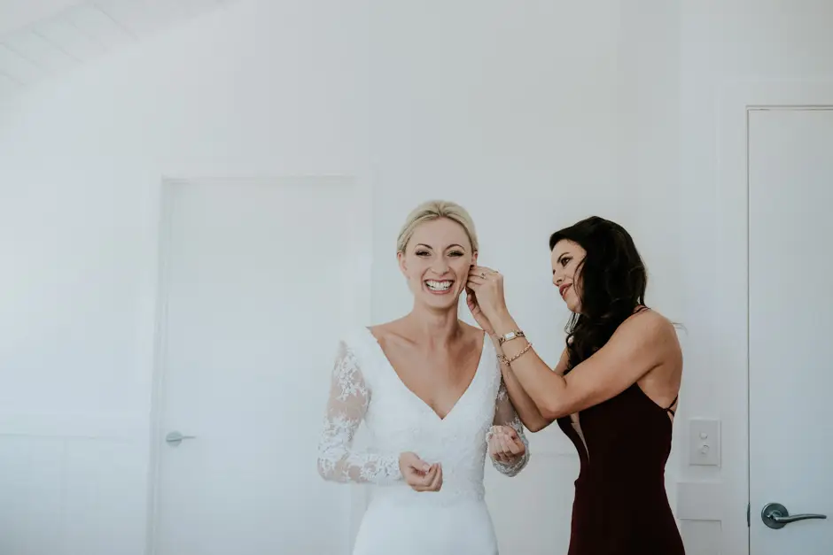 Jessica and a bridesmaid laughing as the last details are finished, Goremans Road
