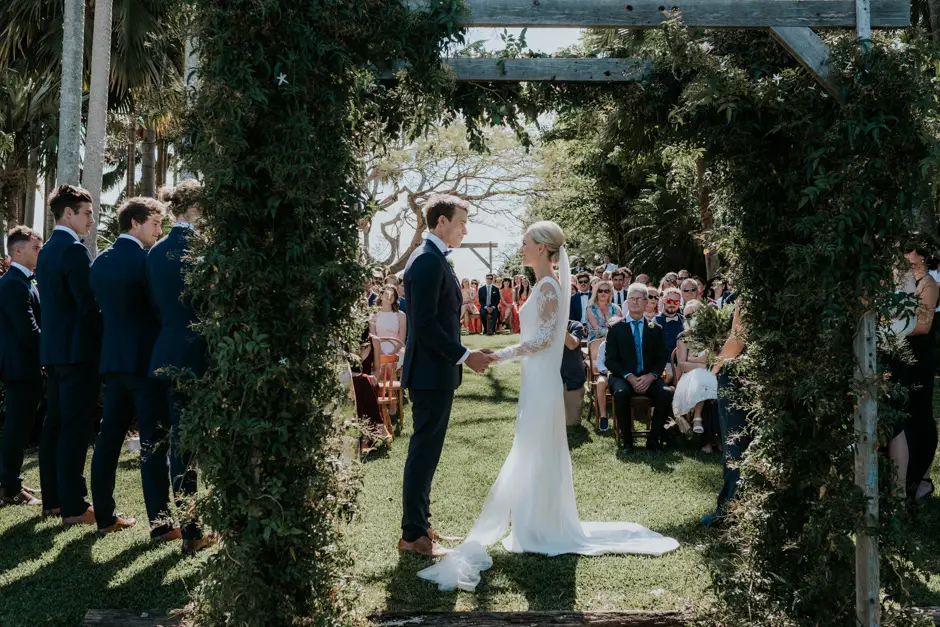 Jessica walking down the greenery-covered aisle towards Jarrod, Eureka