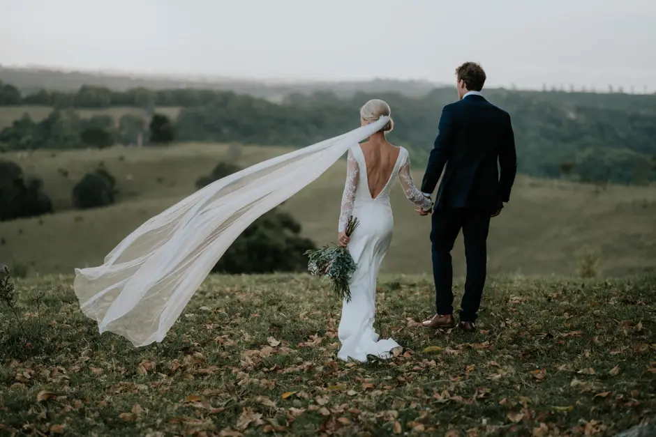 Jessica's veil blowing out behind her as they walk the hillside, Goremans Road