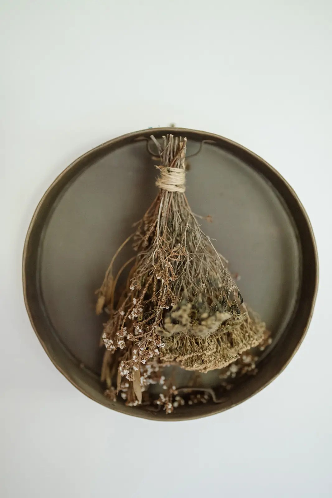 A dried floral wreath hanging in a round mirror, Newrybar