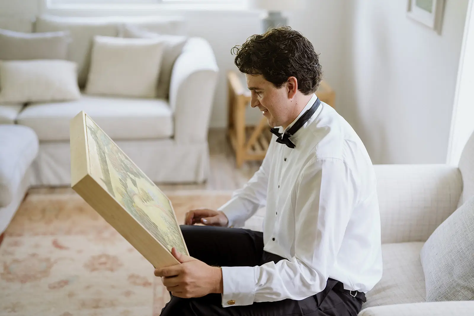 Tom lifting a framed painting from its wrapping, Newrybar