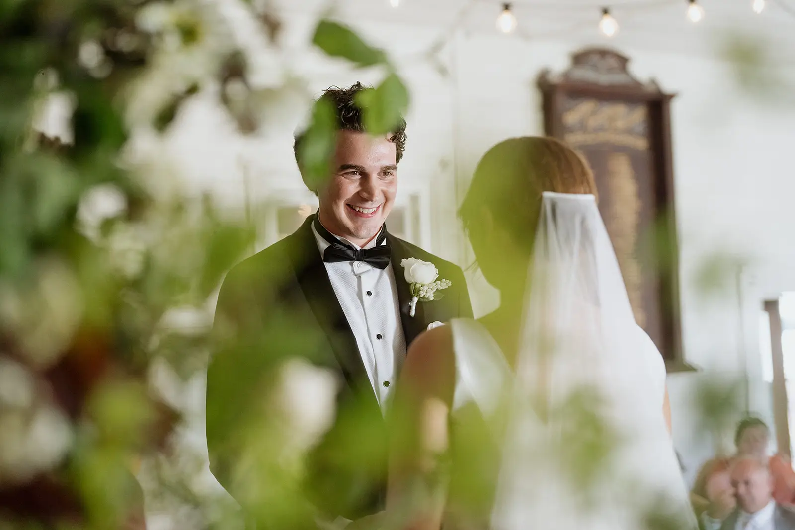 Tom smiling through the greenery during the ceremony, Newrybar