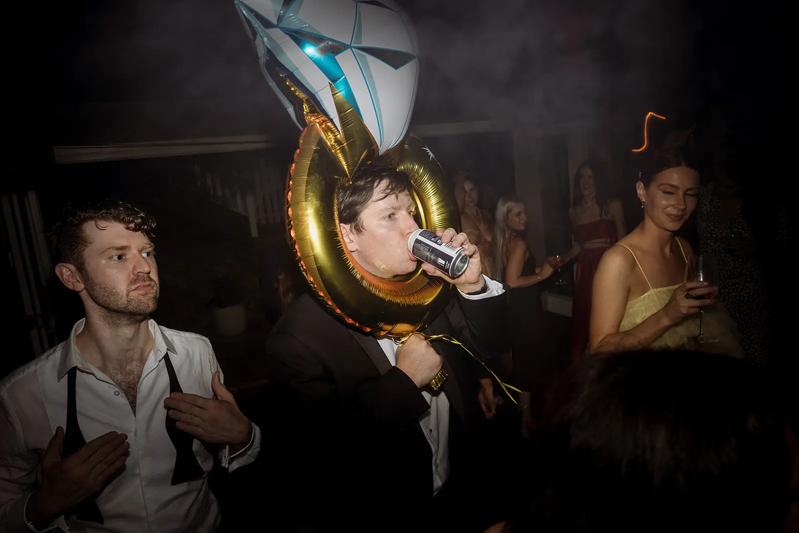 A guest drinking through a giant gold ring balloon on the dance floor, Harvest Newrybar
