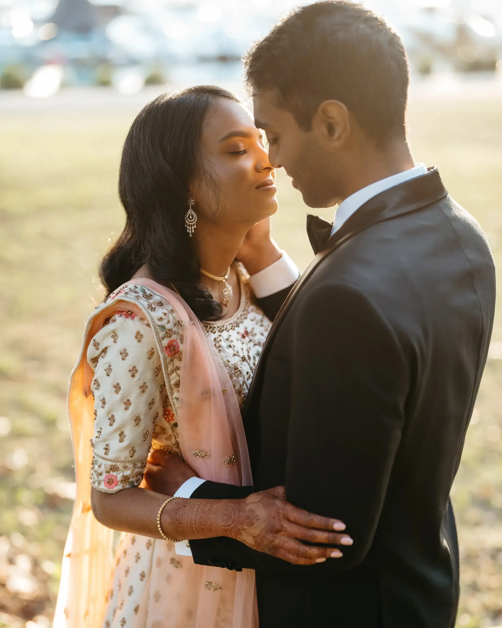 A couple forehead to forehead, the bride in a peach embroidered lehenga