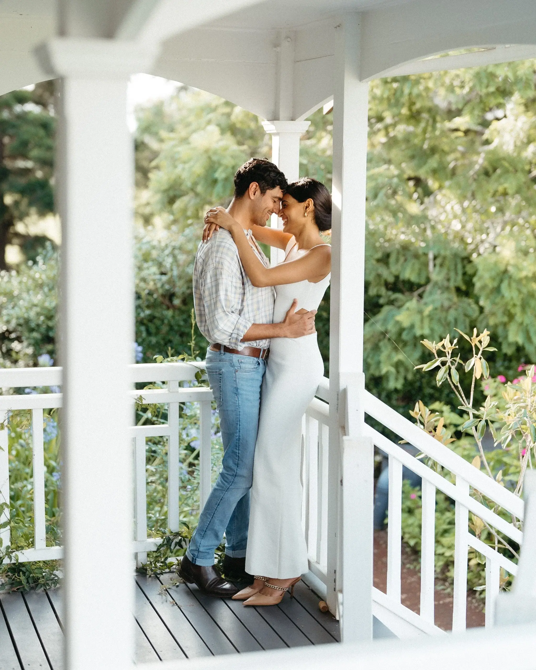 A couple embracing on a white timber verandah
