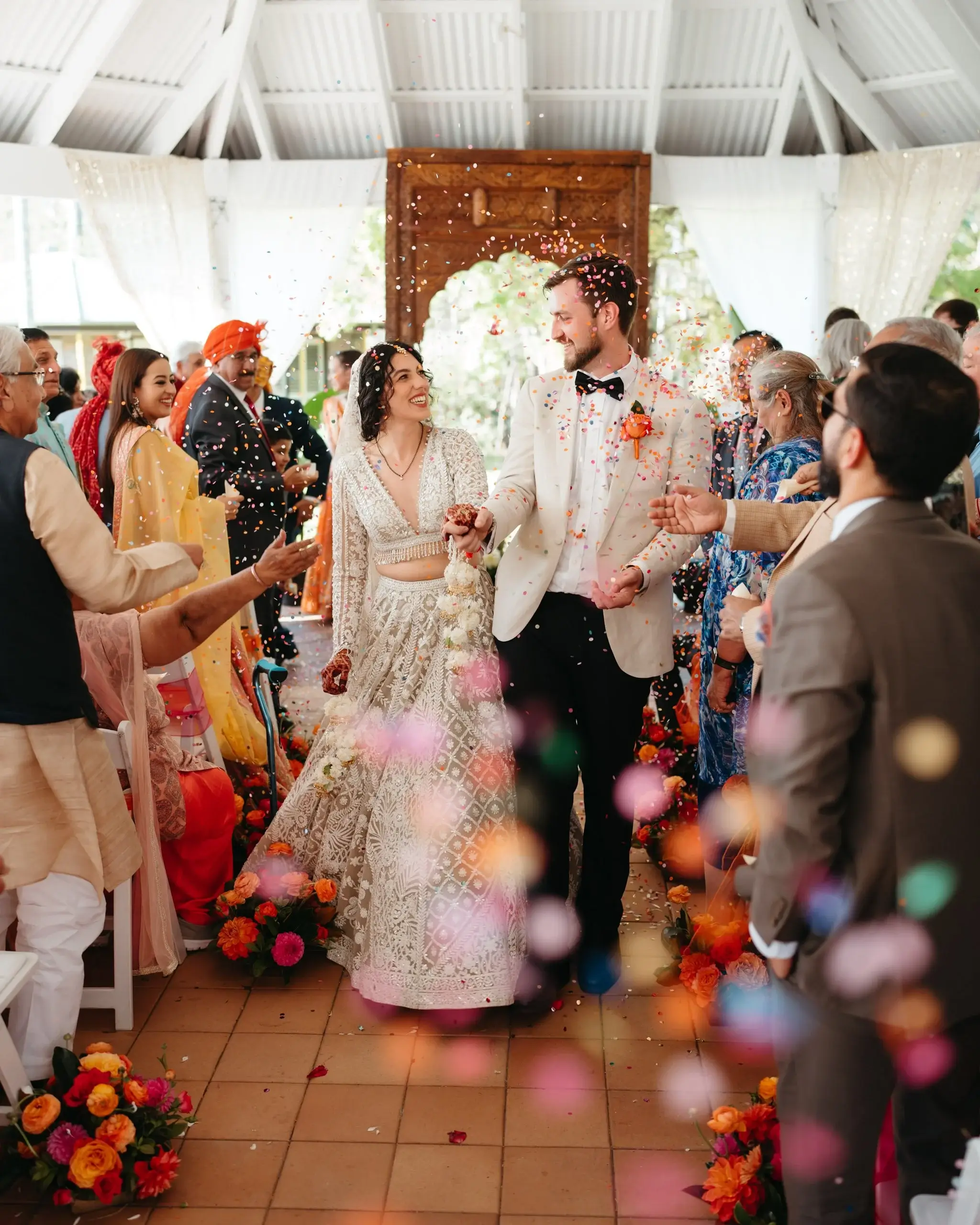 Newlyweds walking out through a shower of confetti, guests lining both sides