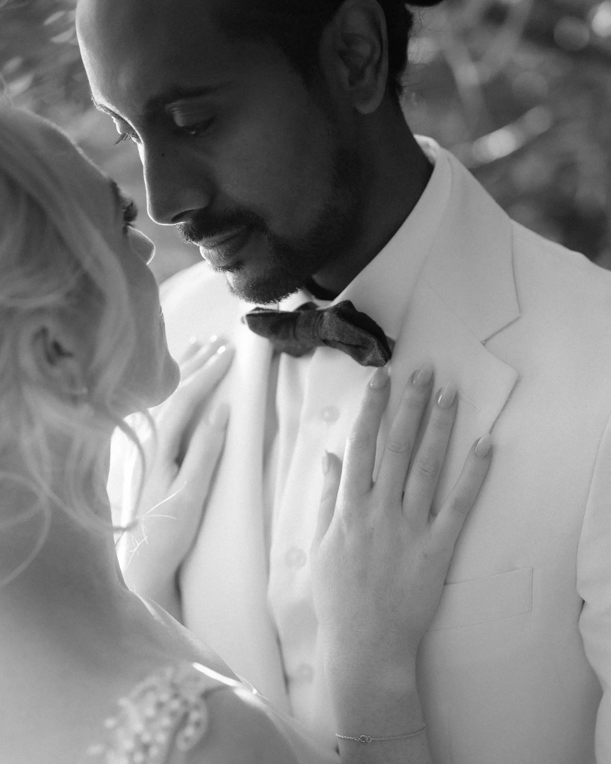 Black and white close-up of a bride’s hand resting on the groom’s chest