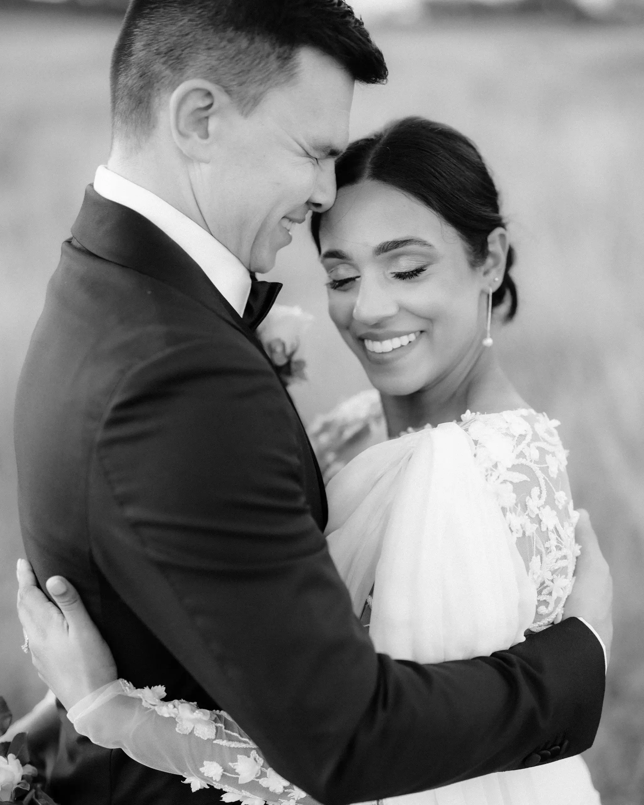 Black and white photograph of a couple holding each other, both smiling