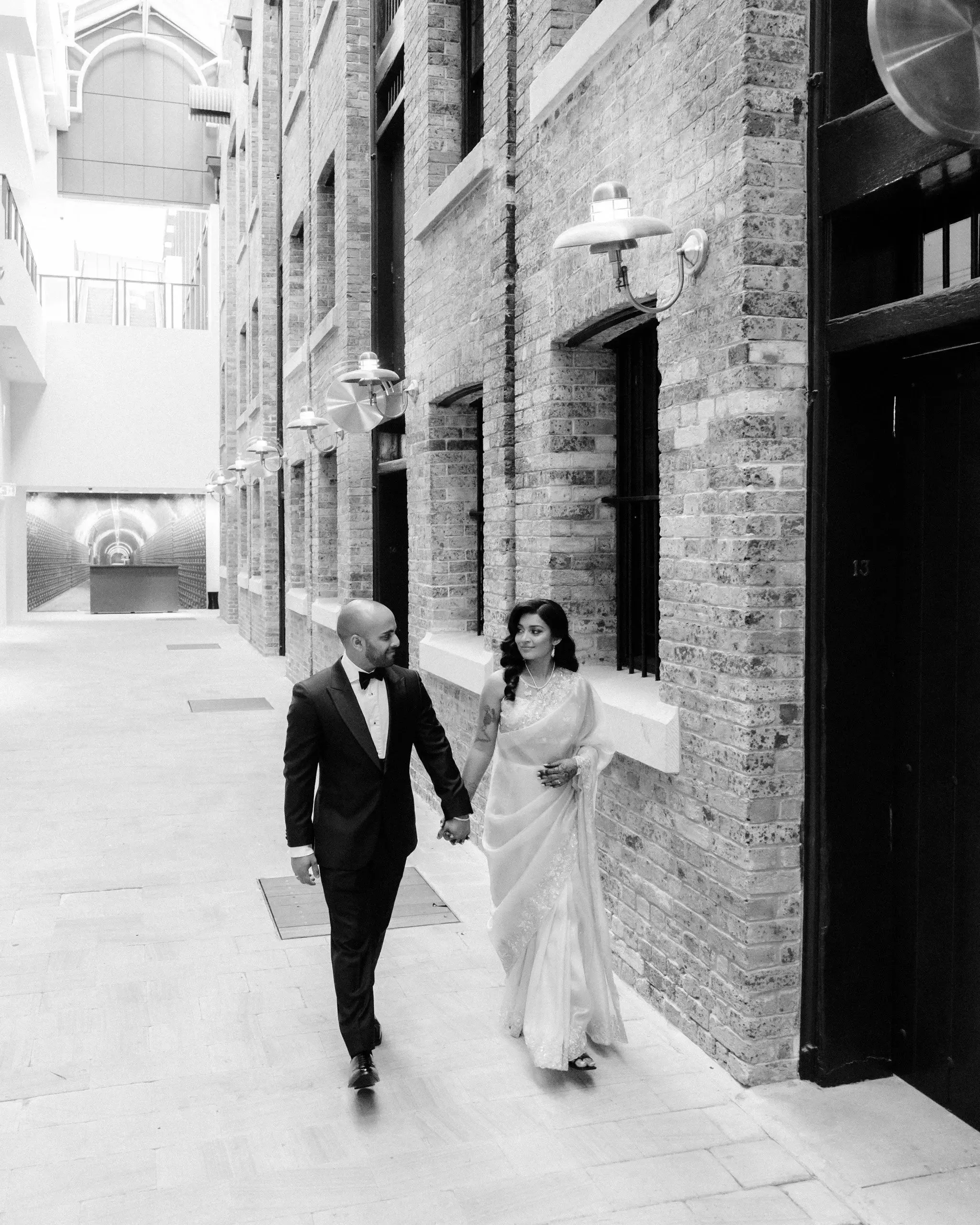 Black and white photograph of a couple walking a brick laneway