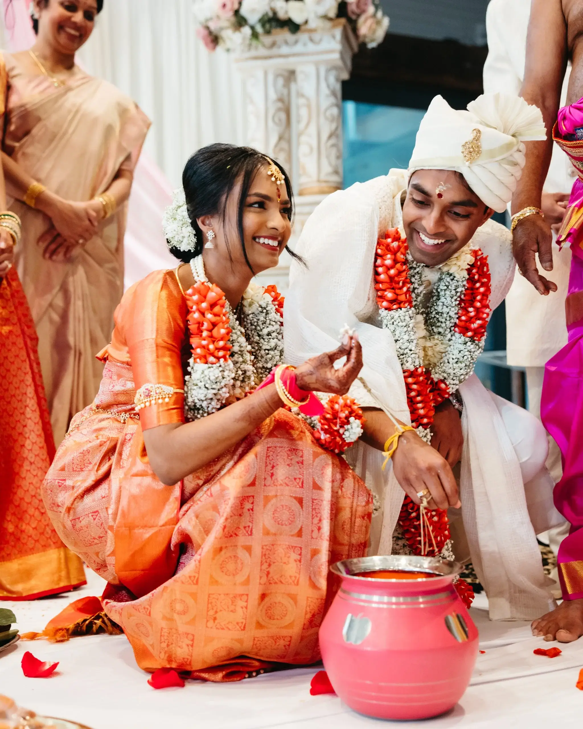 A couple in orange and white traditional dress seated together during a ritual