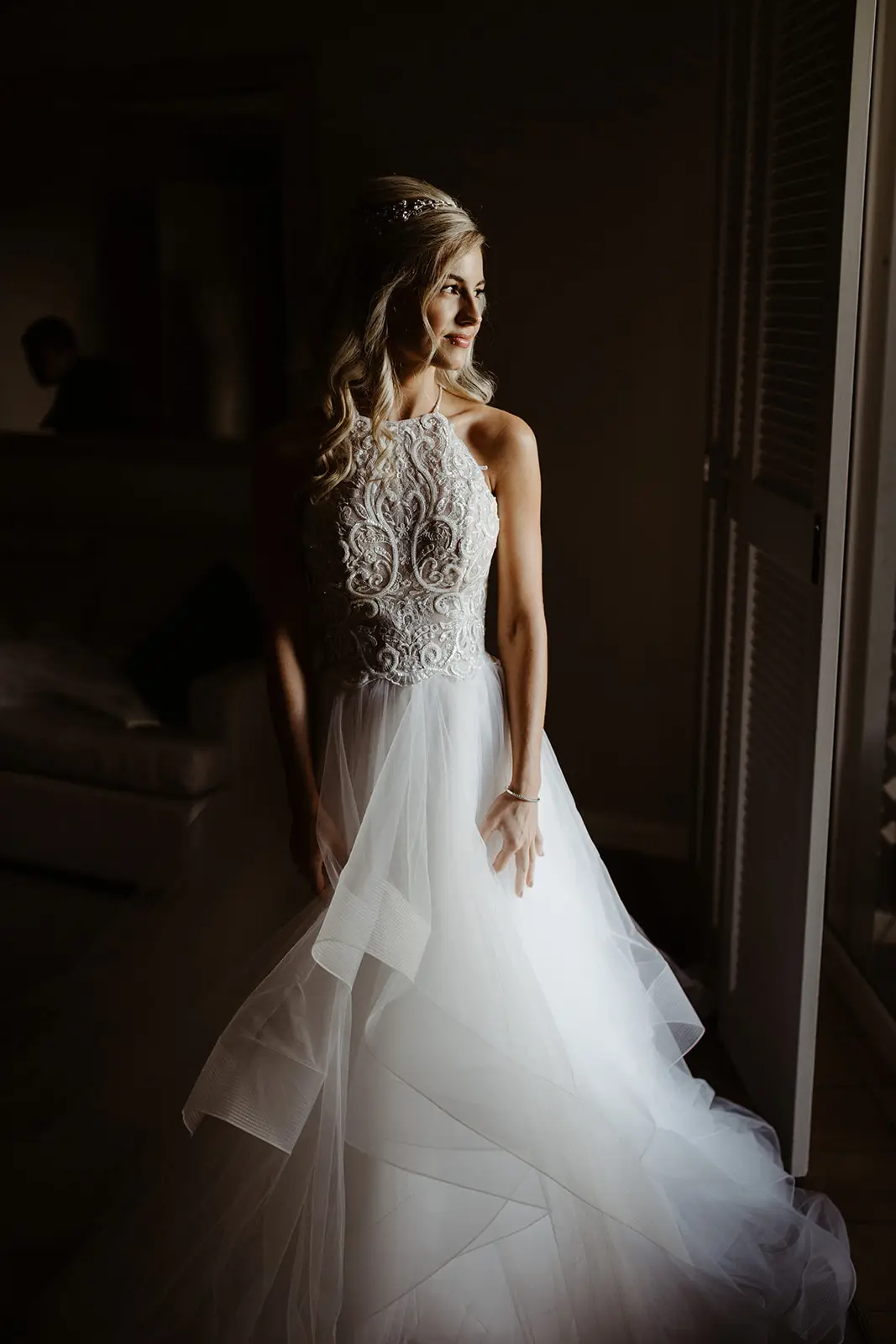 A bride in a tiered tulle gown standing in the light of the suite doorway, InterContinental Sanctuary Cove