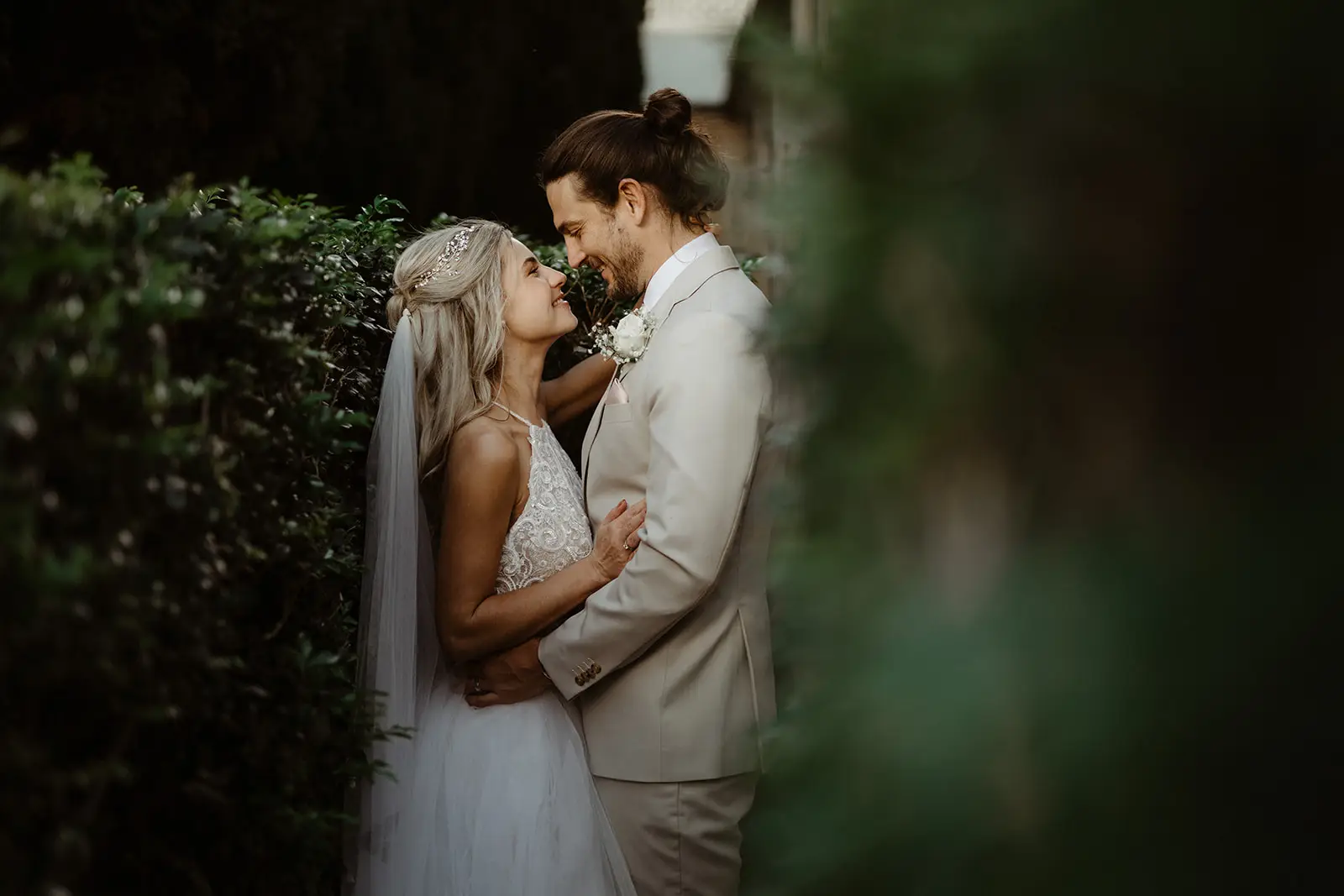 A couple forehead to forehead against a wall of dark green foliage, InterContinental Sanctuary Cove
