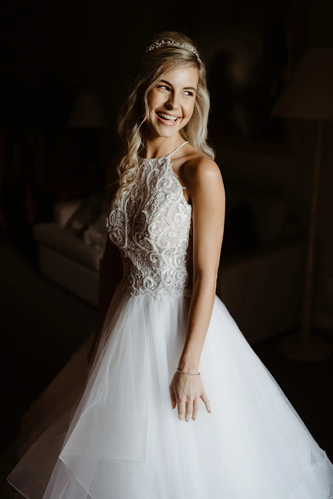 A bride in a tiered tulle gown turning to the window light in the suite, InterContinental Sanctuary Cove