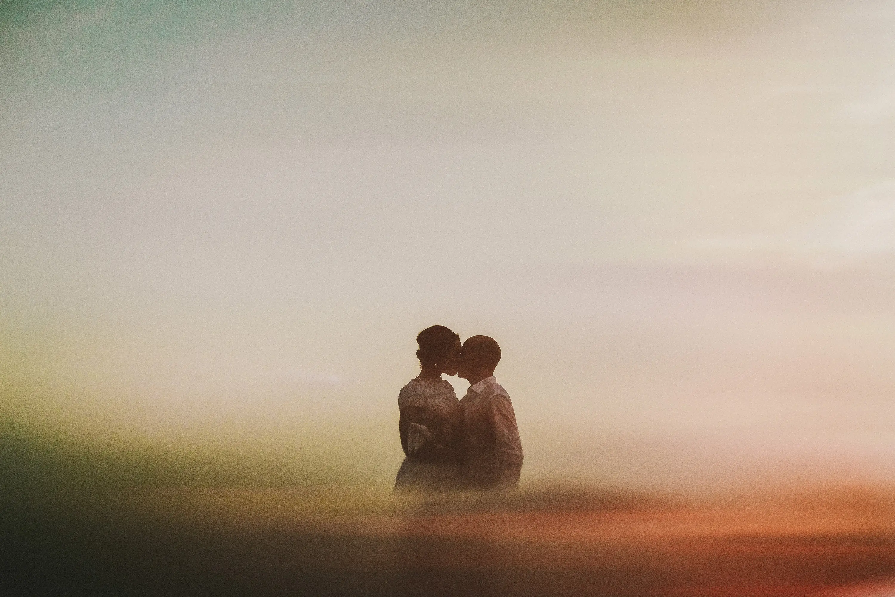 Couple kissing in golden mist at dusk
