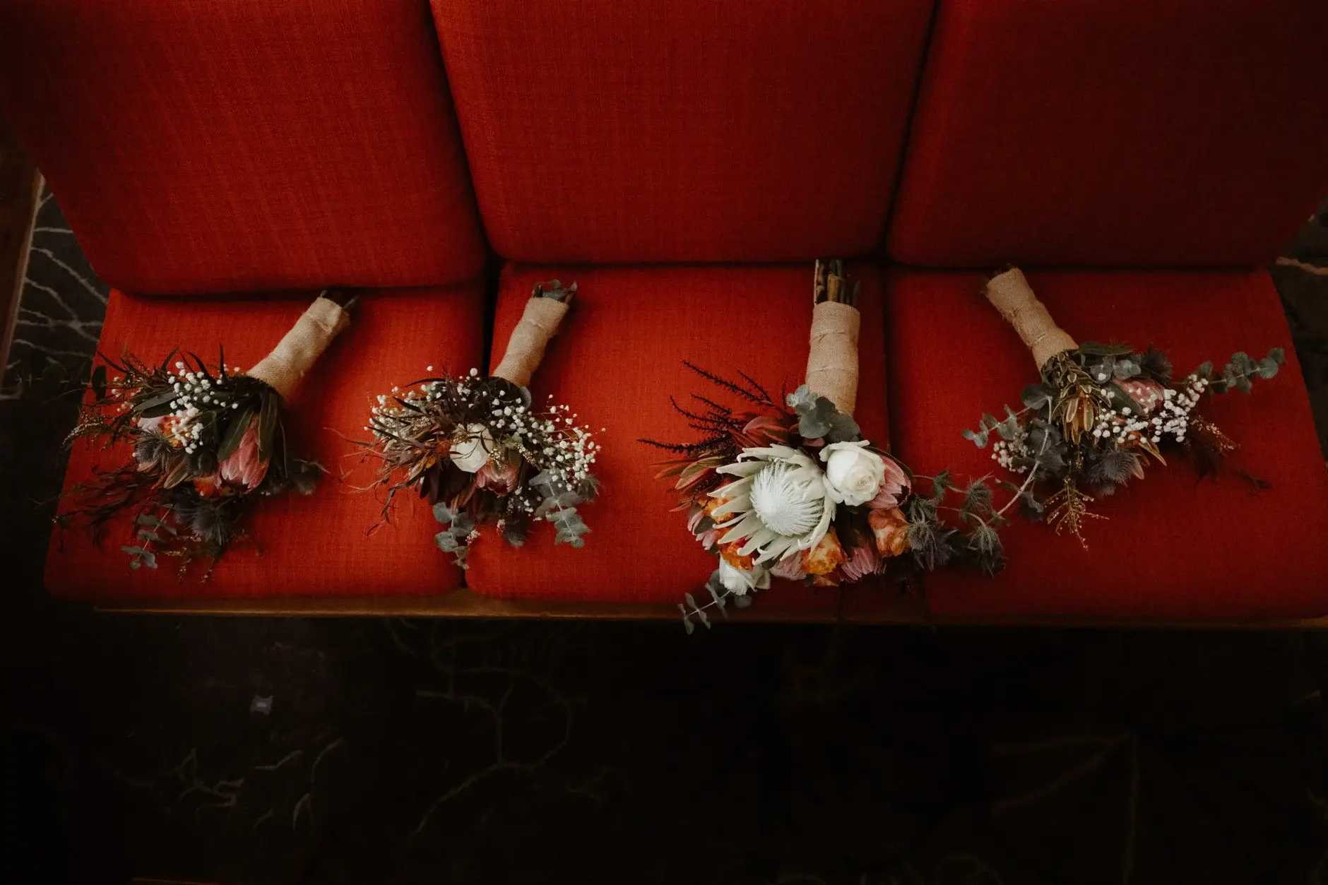 The four buttonholes and bouquets laid out on a red banquette, The Old Clare Hotel