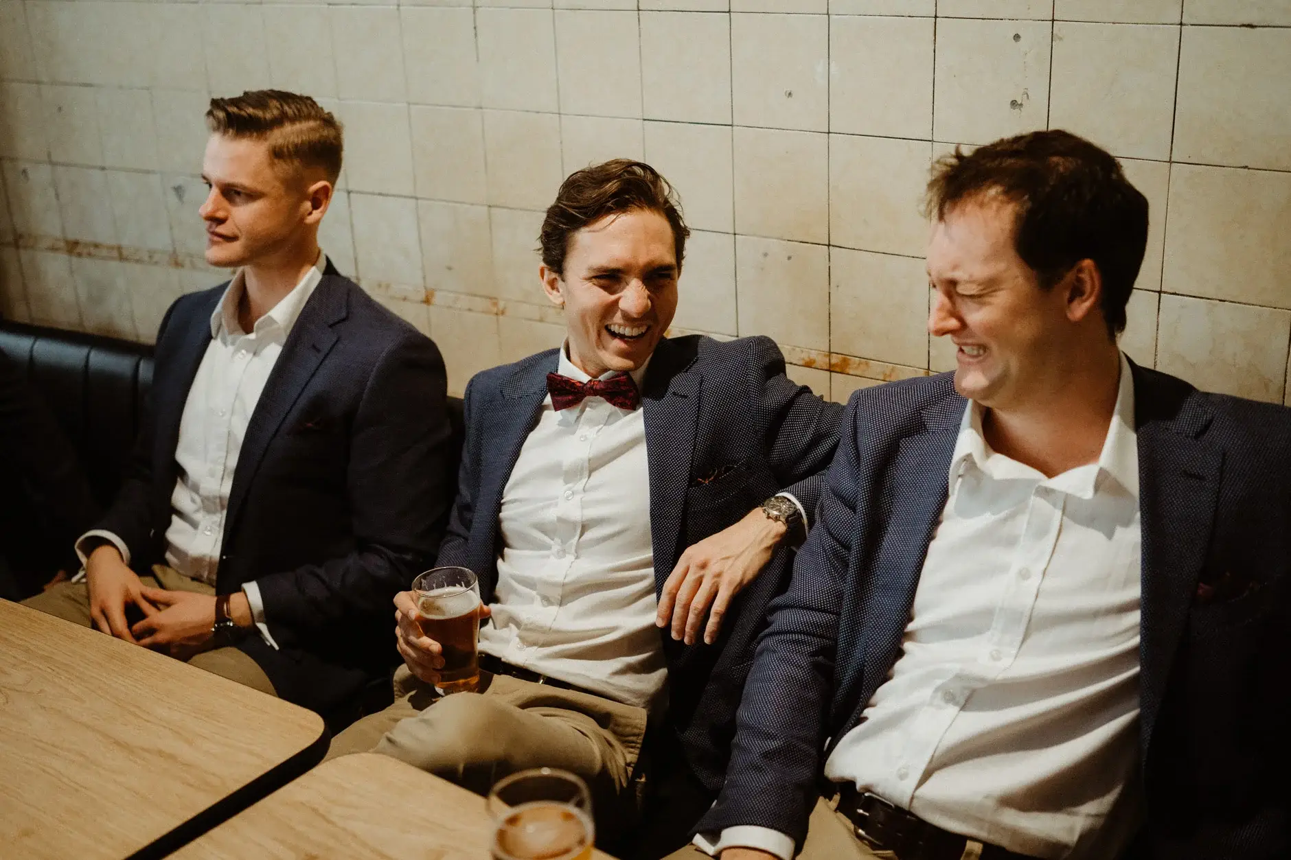 Three of the groomsmen with drinks on the banquette, The Old Clare Hotel