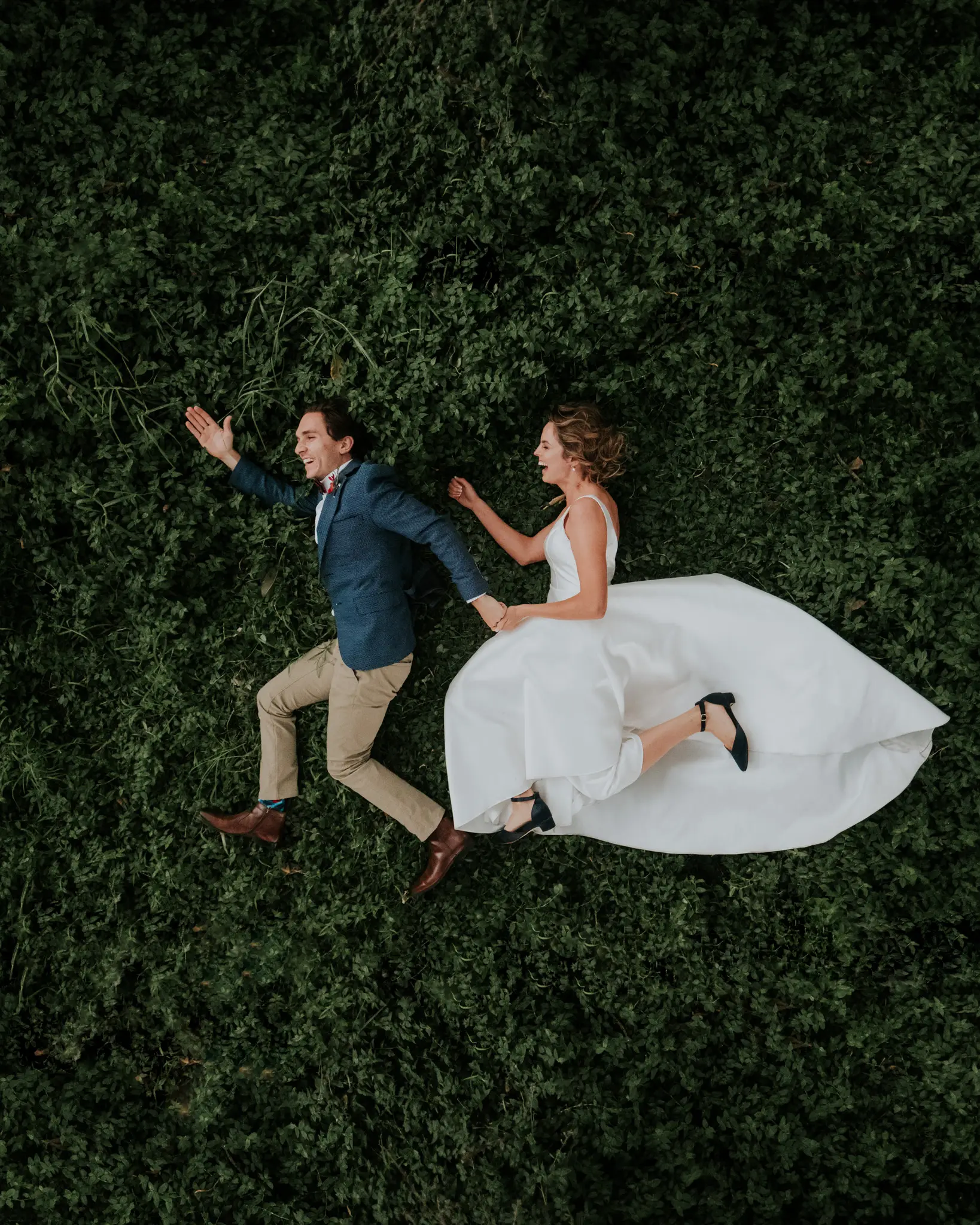 Couple collapsing in laughter on a bed of clipped green