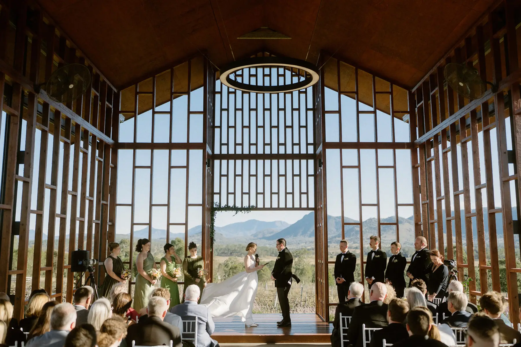 The ceremony under way with Nicole's veil lifting in the breeze and the mountains through the open chapel wall, Kooroomba Vineyard and Lavender Farm