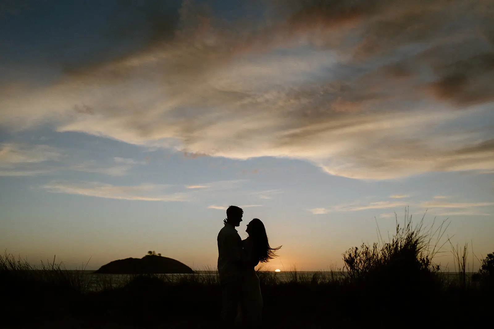 The couple silhouetted against a sunset sky, Lord Howe Island