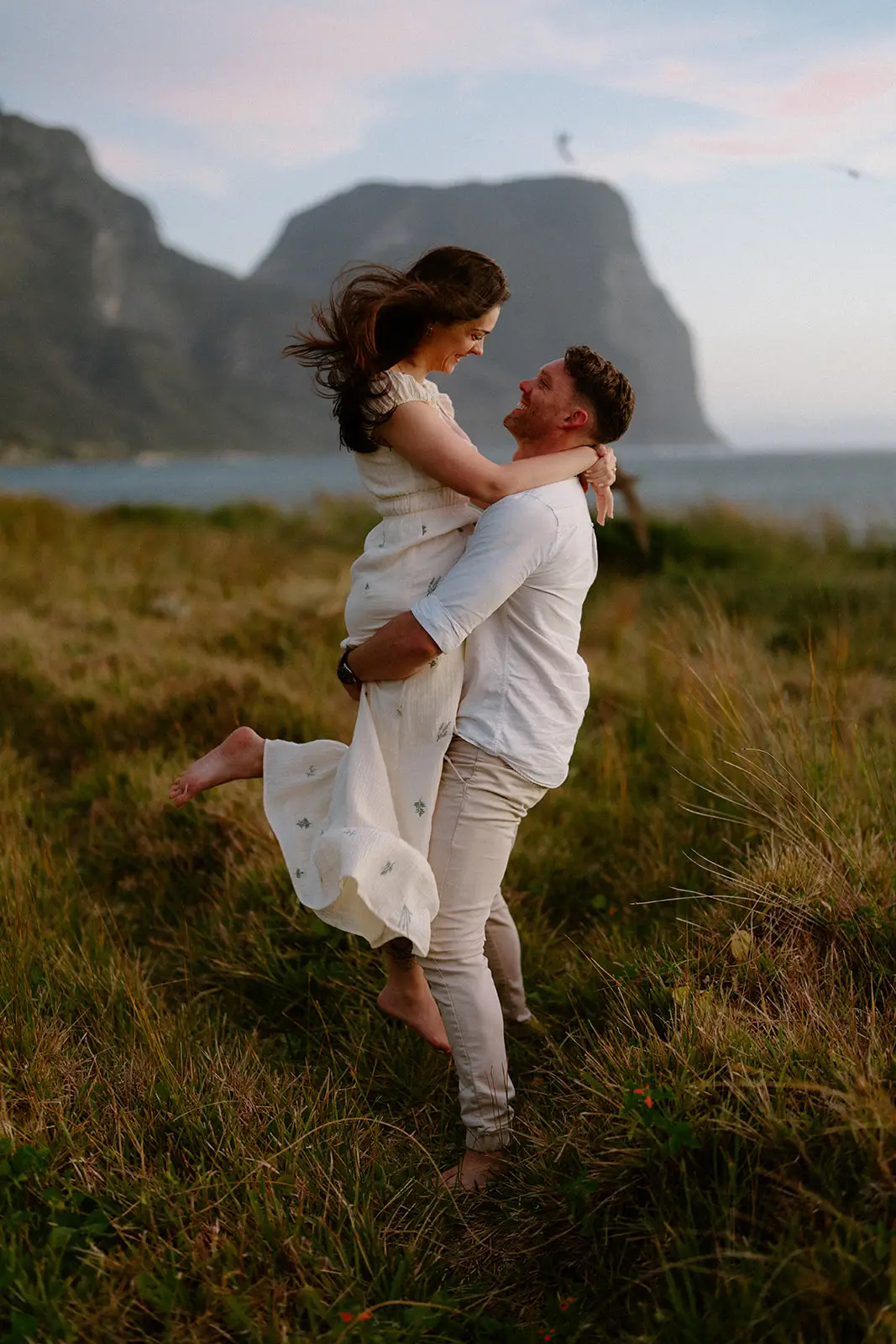 Brent spinning Mel in the grass below the mountains, Lord Howe Island