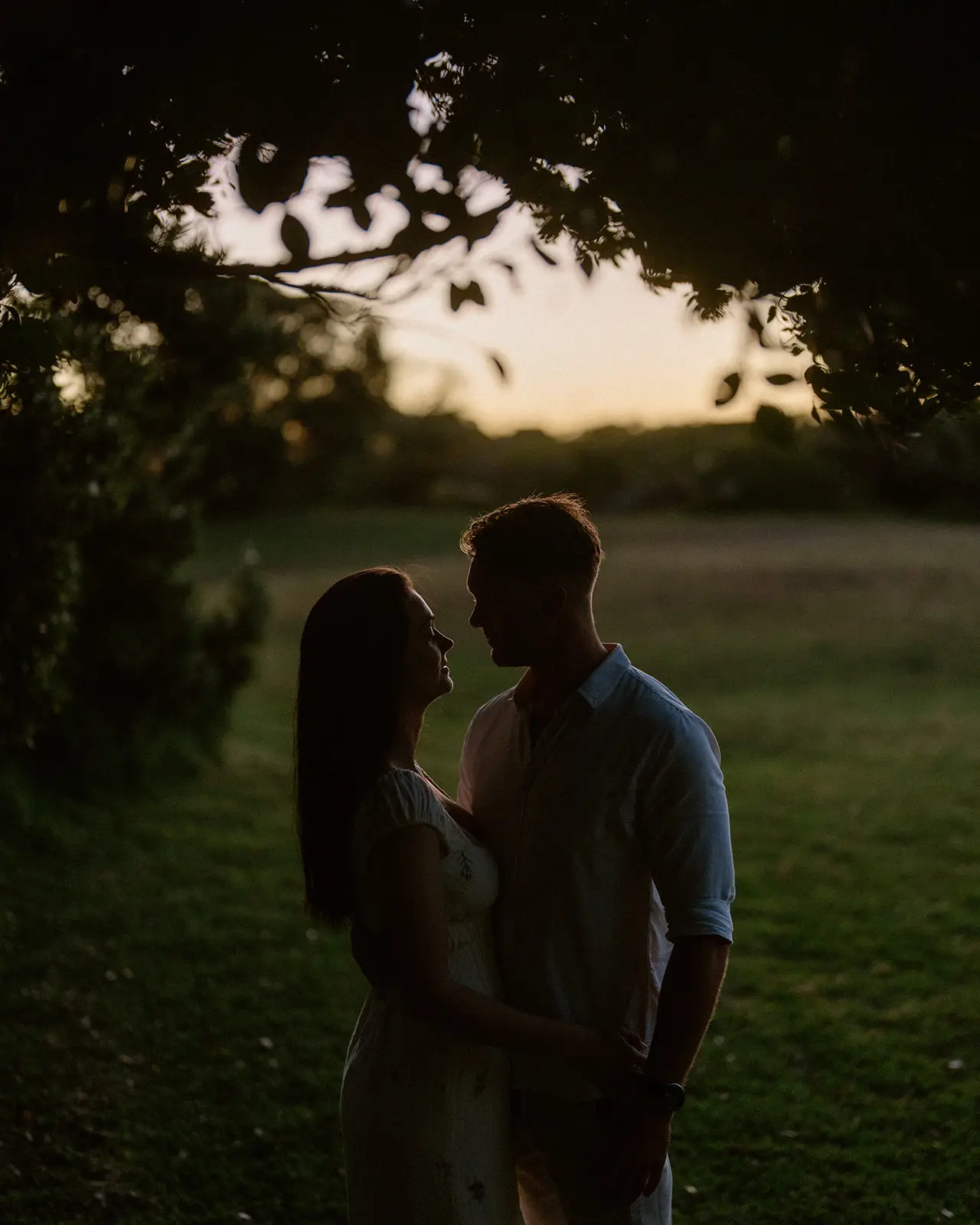 Mel and Brent silhouetted beneath a tree at sunset, Lord Howe Island